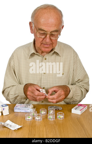Portrait vertical d'un vieux monsieur l'organisation de son médicament hebdomadaire en conteneurs individuels dans le cadre d'une tour de stockage. Banque D'Images