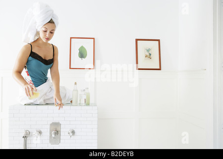 Jeune femme versant de l'huile dans la baignoire. Banque D'Images