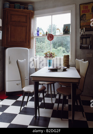 Années 80, table et meubles chaises blanches en cuisine salle à manger avec damier noir et blanc de sol en vinyle Banque D'Images