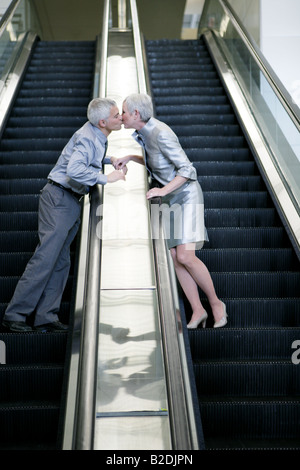 Mature couple kissing des escaliers mécaniques. Banque D'Images