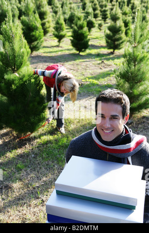 Jeune couple à l'arbre de Noël avec beaucoup de cadeaux. Banque D'Images
