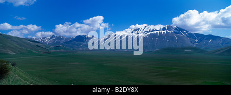 Le vaste plateau du Piano Grande avec le village perché de Castellucio et montagnes Monti Sibillini Ombrie Italie Banque D'Images