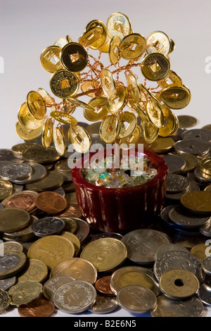 Le Feng Shui Arbre d'argent debout sur un tas de pièces de monnaie du monde entier Banque D'Images