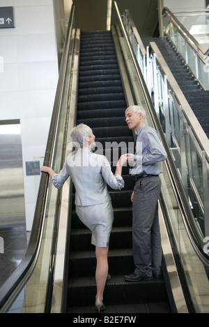 D'âge mûr sur les escaliers mécaniques à l'aéroport. Banque D'Images