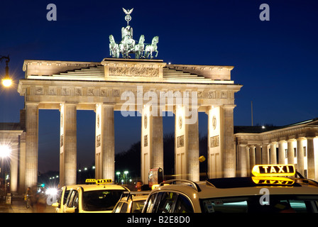 Des taxis près de memorial gate allumé jusqu'à la tombée de la porte de Brandebourg Berlin Allemagne Banque D'Images