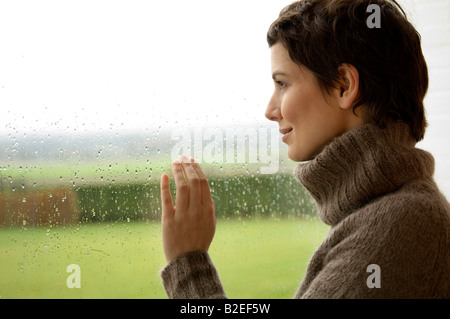 Mid adult woman looking out à travers une fenêtre Banque D'Images