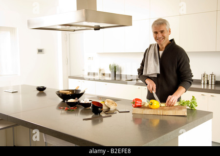Portrait d'un homme mûr hacher les légumes dans la cuisine Banque D'Images