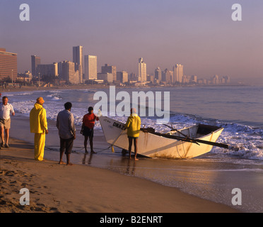 Les pêcheurs trek dans un crochet de transport sur le front de mer de Durban avec les tours d'habitation dans l'arrière-plan Banque D'Images