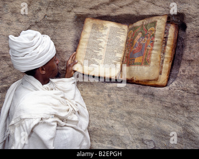Un prêtre de l'église éthiopienne orthodoxe est une très vieille bible magnifiquement illustré, à côté de l'entrée. Banque D'Images