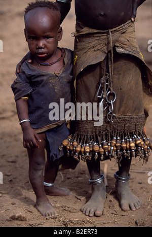 Une jeune fille Dassanech tient son petit frère. Elle porte une jupe en cuir avec une bordure de bois et de métal tassles. Banque D'Images