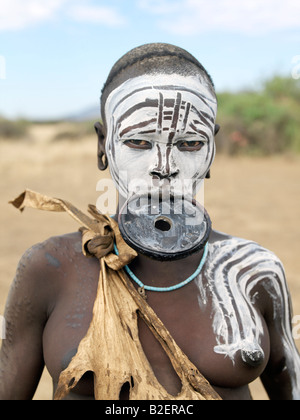 Une femme Mursi décorées avec scarification visage et corps porte une grande lèvre d'argile plaque. Banque D'Images