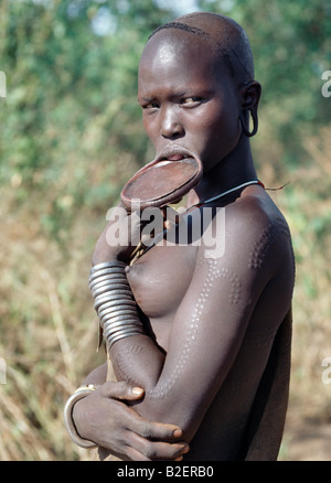 Une femme Mursi avec scarification attrayant porte une grande lèvre d'argile plaque. Banque D'Images