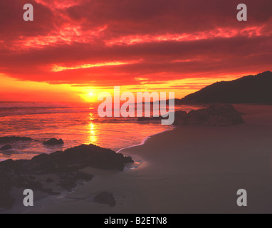 Nuages rouges lumineuses reflètent dans l'eau au lever du soleil Banque D'Images