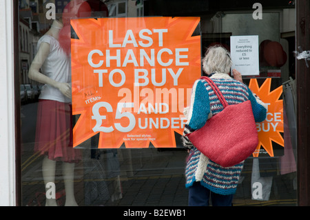 Femme à la fenêtre dans un magasin au cours des bonnes affaires en vente à £5 ou moins clothes shop fermer vente Aberystwyth Wales UK Banque D'Images