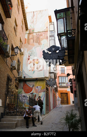 Espagnol Espagne Toledo trois garçons adolescents assis debout dans la petite rue latérale peint murale sur le côté du bâtiment Banque D'Images