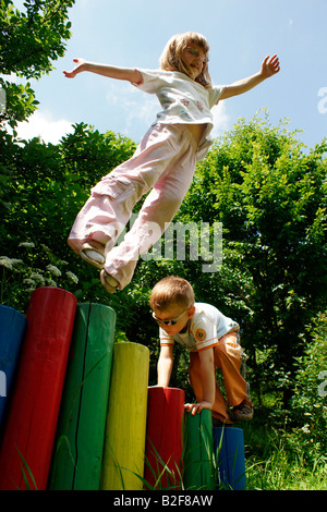 Jeune petite fille blonde kid jumping heureux à l'extérieur de poteaux colorés aux enfants jeux pour enfants en Slovaquie Banque D'Images