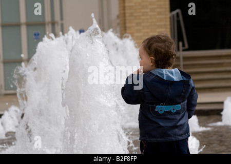 Jeune garçon debout devant la fontaine, vue arrière Banque D'Images