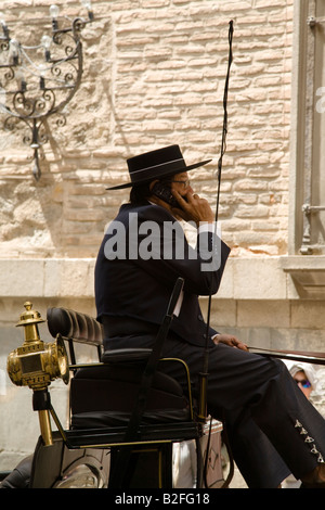 Espagne Toledo Conducteur de chariot et deux chevaux noirs talk on cell phone d'attendre à l'extérieur church costume et chapeau Banque D'Images