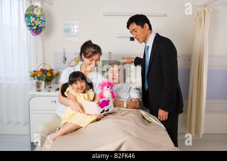 Femme couchée sur le lit et souriant avec sa famille à côté d'elle Banque D'Images