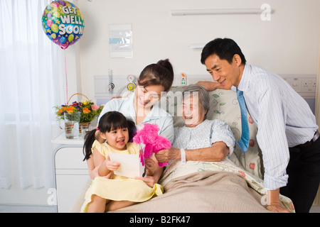 Femme couchée sur le lit et souriant avec sa famille à côté d'elle Banque D'Images