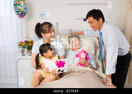 Femme couchée sur le lit et souriant avec sa famille à côté d'elle Banque D'Images