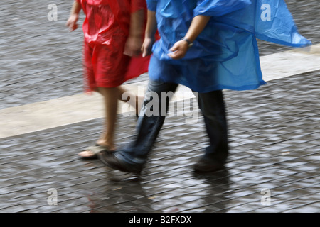 Couple portant des capes manteau imperméable dans la pluie Banque D'Images