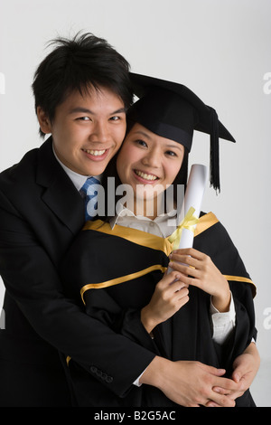 Portrait of a young man hugging a young female graduate and smiling Banque D'Images