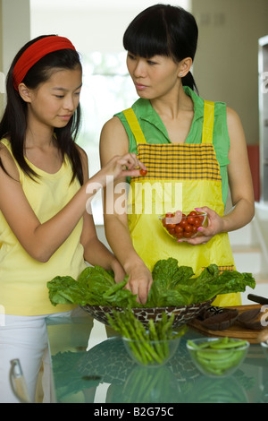 Mid adult woman with her daughter la préparation des aliments dans une cuisine Banque D'Images