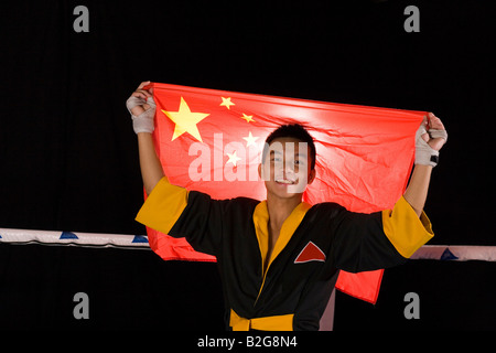 Portrait d'un jeune homme tenant un drapeau chinois dans un ring de boxe Banque D'Images