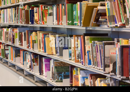 Gros plan d'une étagère dans une bibliothèque, remplie de livres de différentes tailles et couleurs. Banque D'Images