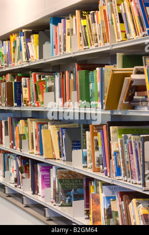 Gros plan d'une étagère dans une bibliothèque, remplie de livres de différentes tailles et couleurs. Banque D'Images