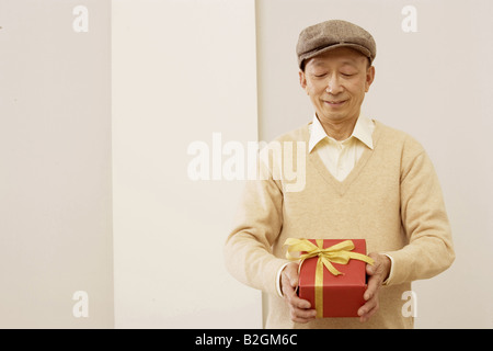 Close-up of a senior man holding a présent et souriant Banque D'Images
