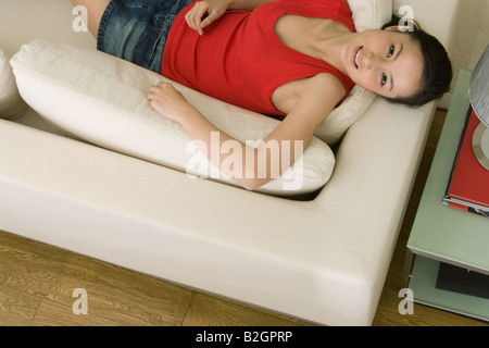 Portrait of a young woman reclining on a couch and smiling Banque D'Images
