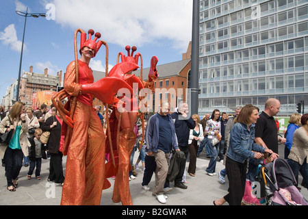 Liverpool Merseyside England UK Juillet un homme et femme marche sur des échasses habillé comme les crabes parmi les foules se pressant Banque D'Images