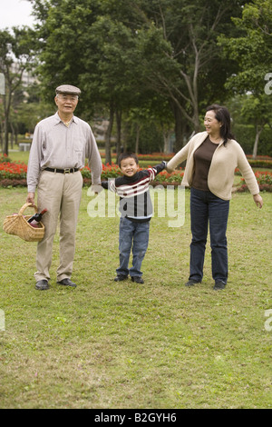 Couple avec leur petit-fils debout dans un parc et smiling Banque D'Images