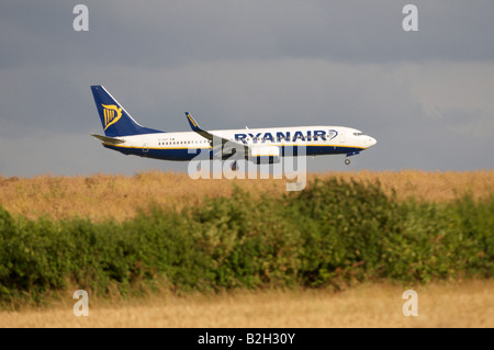 Boeing 737 de Ryanair Stansted effet Brume de chaleur apparaissant à la terre sur un champ de blé vallonnés Banque D'Images