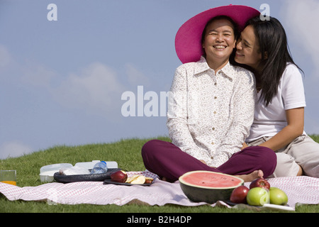 Senior woman with her daughter sitting sur une couverture de pique-nique et souriant Banque D'Images