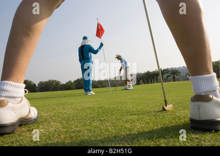Up d'un joueur de golf avec deux joueurs à l'arrière-plan Banque D'Images