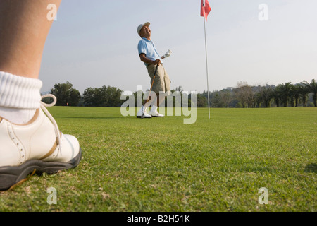 Up d'un joueur de golf avec un homme mûr en jouant au golf dans l'arrière-plan Banque D'Images