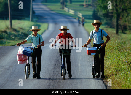 Les enfants Amish en plaine sur les vêtements traditionnels scooters sur leur chemin de retour de l'école, comté de Lancaster, Pennsylvanie, USA Banque D'Images