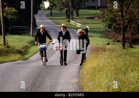 Les enfants Amish en plaine sur les vêtements traditionnels scooters sur leur chemin de retour de l'école, comté de Lancaster, Pennsylvanie, USA Banque D'Images