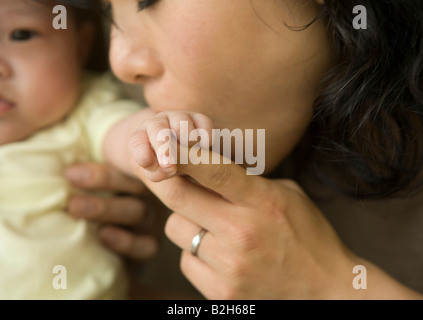 Mid adult woman kissing her daughter's hand Banque D'Images