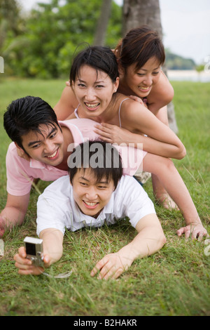 Deux jeunes couples de prendre une photo d'eux-mêmes avec un appareil photo numérique Banque D'Images