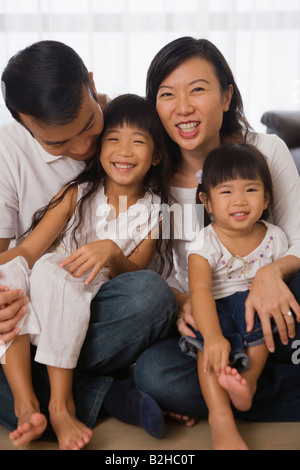 Couple assis avec leurs deux filles sur le sol, à Singapour Banque D'Images