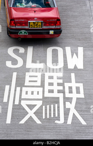 Grande Enseigne peinte sur l'avertissement de route pour conduire lentement à Hong Kong, Chine Banque D'Images