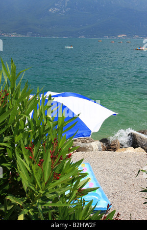 Un parasol sur une plage au lac de garde sur le matelas colorés inflateable fantastique maison de sable ou de droit Banque D'Images