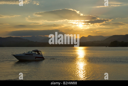 Un croiseur à moteur sur le lac Windermere, avec le soleil sur le Langdale Pikes, Parc National de Lake District, Cumbria, Angleterre Banque D'Images