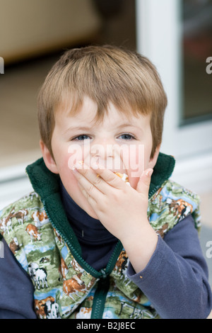 Petit garçon gâteau se bousculer dans sa bouche. Banque D'Images