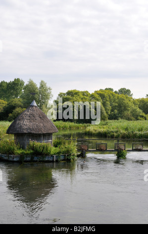 Cabane de pêcheurs de chaume et osier pièges à anguilles de l'autre côté de la rivière La rivière Test, Hampshire, Angleterre Banque D'Images