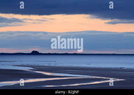 L'île de Lindisfarne (saints) silhouetté contre un coucher de soleil d'été à l'échelle de Budle Bay sur la côte de Northumbrie, Angleterre Banque D'Images